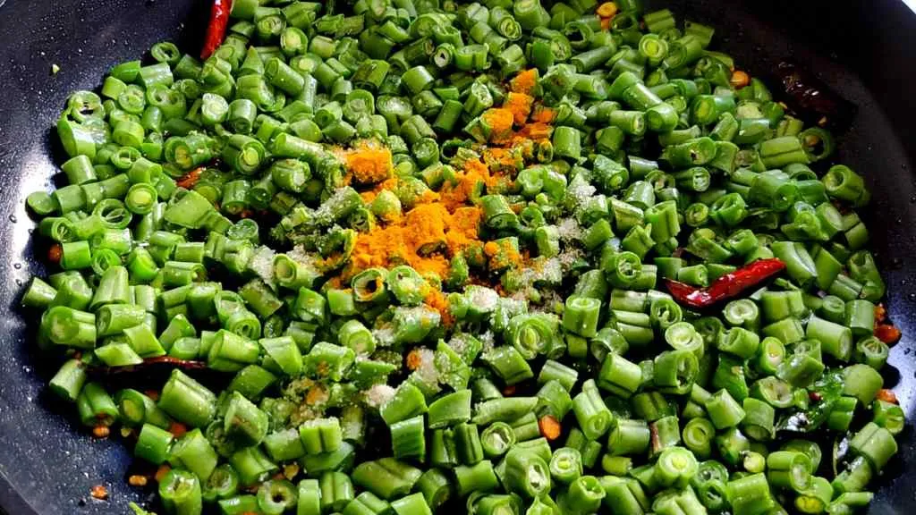 Green beans poriyal: add in green beans, turmeric, and salt.