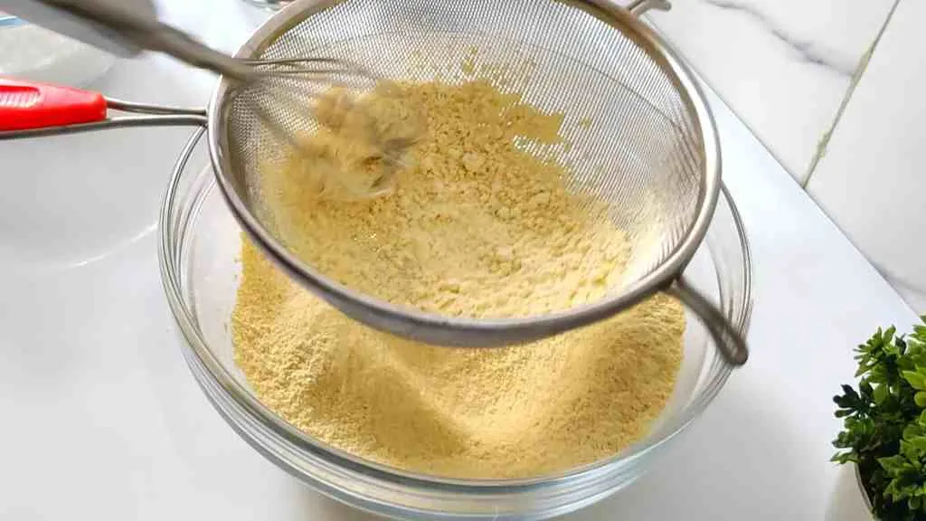 Use a sifter to sift/seive the besan flour and remove all clumps.
In a pan, add 2 cups of ghee. Bring the mixture to a boil and simmer.
In a separate large non-stick pan, add the sugar and water. Bring the mixture to a boil and stir until the sugar reaches a one string consistency. One string consistency is where you press the cooled sugar syrup between your thumb and index finger and a single string of sugar stretches out when you spread your thumb and finger apart. Keep the flame on low heat.
Slowly add the sieved gram flour to the sugar mixture in batches, while continuously stirring to avoid lumps.
Take a ladleful of the hot ghee mixture and pour it into the besan mixture. Stir until the ghee is completely absorbed. Repeat this process until no more ghee mixture will be absorbed by the besan mixture.
Once the besan and sugar mixture is completely saturated with the ghee mixture, transfer the mixture to a greased tray, loaf pan, or square pan. Press the mixture into the mold.
Allow the mixture to cool for 5 minutes before cutting into desired pieces witha. sharp knife. After 20 minutes, you can separate the pieces.
Your Mysore Pak is now ready to serve.